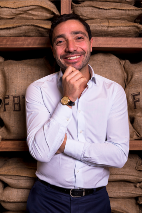 Uomo sorridente, esperto di cioccolato Cioccolatitaliani, con sacchi di cacao.