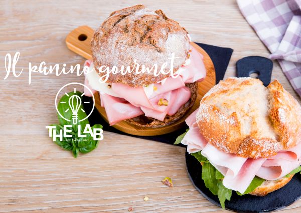 Due panini gourmet Délifrance con mortadella, rucola e formaggio su taglieri. Corso online per panino perfetto.