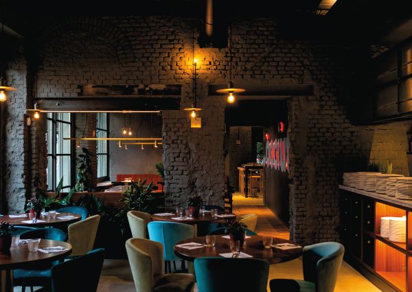 Interni eleganti del ristorante Cocciuto: tavoli rotondi, sedie colorate, pareti in mattoni e luci soffuse. Cucina fusion e pizza.