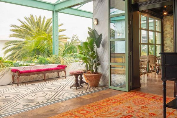 Interni lussuosi di Gucci Osteria: divano rosso, piante tropicali e arredo elegante. Food e fashion a braccetto.