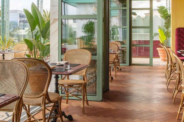 Interni Gucci Osteria: tavoli apparecchiati, sedie in rattan, pavimenti in legno. Design food e fashion.