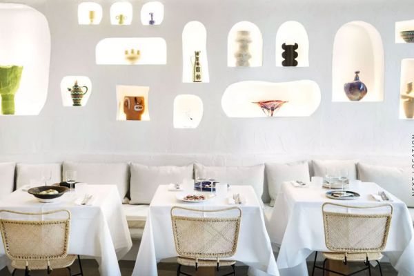 Interni di ristorante di lusso. Tavoli imbanditi, sedie di design e nicchie con oggetti d'arte. Food e fashion.