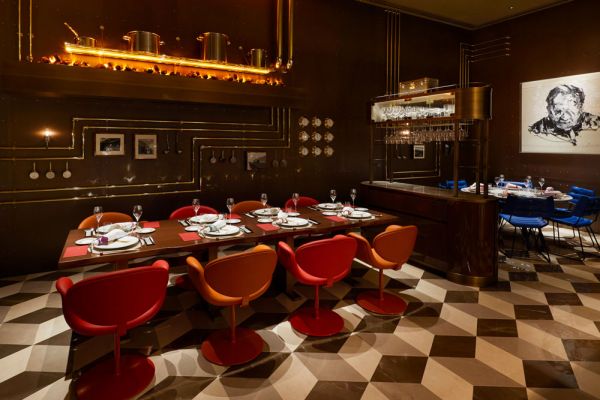 Interni del ristorante Louis Vuitton: tavolo imbandito, sedie colorate, dettagli di design. Food e fashion a Parigi.