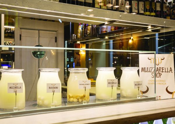 Vetrine di Muu Muuzzarella Shop con mozzarella fresca, bocconcini e affumicati. Eccellenza casearia locale.