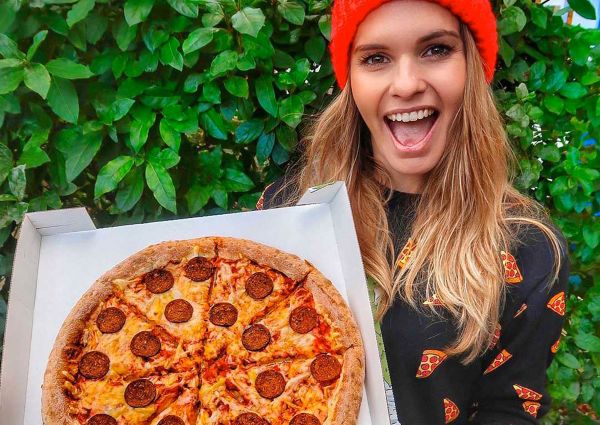 Papa John's UK assume CVO: Donna sorridente con pizza vegana. Novità menu vegano Papa John's.