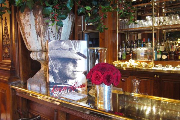 Ralph's: food e fashion. Bar elegante con fiori rossi, poster Ralph Lauren e bottiglie. Design d'interni raffinato.