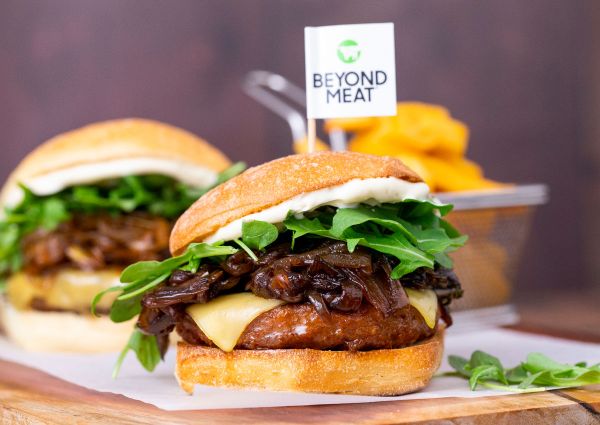 Burger plant-based Beyond Meat. Panino vegano con formaggio, cipolle caramellate e rucola.