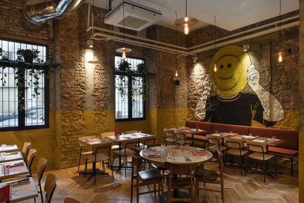 Interno accogliente di Berberè a Milano. Muri in mattoni, murales artistico e tavoli pronti per la pizza. Design unico.