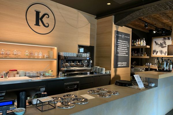 Interno di Kalamaro Piadinaro: banco bar, macchina caffè, logo K. Design moderno e accogliente. #KalamaroPiadinaro #Milano