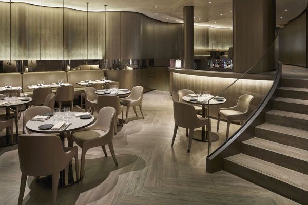 Interni raffinati del ristorante Emporio Armani a Parigi. Tavoli apparecchiati, illuminazione soffusa. Moda e ristorazione Armani.