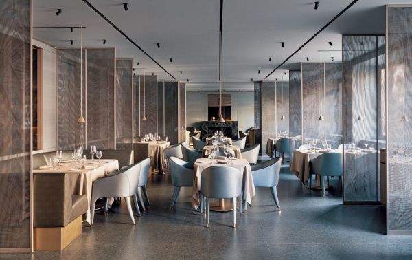 Interni raffinati del ristorante Emporio Armani a Milano. Tavoli apparecchiati, sedie di design.