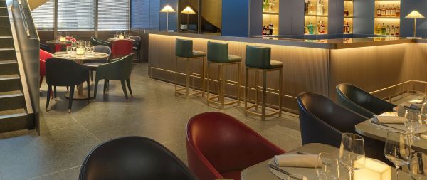Interni raffinati dell'Emporio Armani Ristorante a Milano. Tavoli apparecchiati, sedie di design e bar illuminato.