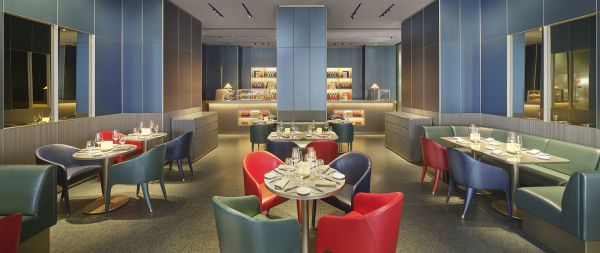 Interni Emporio Armani Ristorante Milano. Tavoli apparecchiati, sedie colorate, atmosfera elegante.