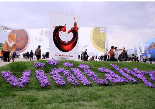 Vinitaly: scritta floreale, padiglioni fiera del vino, visitatori. Evento Vinitaly Verona.