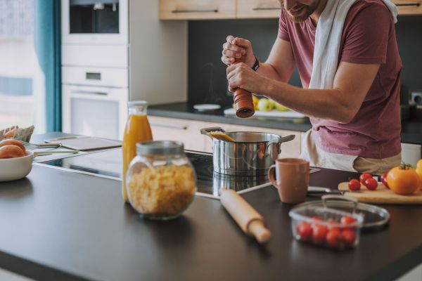 Chef cucina ricetta pasta. Uomo che macina pepe in pentola. Ricette chef stellati contro Coronavirus.