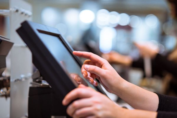 Calo fatturati ristoranti: mano su schermo POS. Ristorazione, tecnologia.