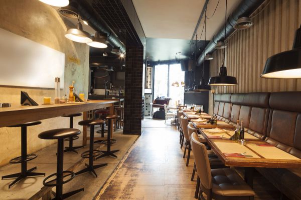 Interno ristorante. Tavoli apparecchiati e bancone. FIPE ristorazione, aiuto imprese.