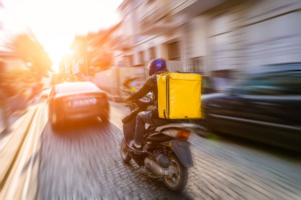 Servizio delivery: rider su scooter con borsa termica gialla per consegna cibo a domicilio. MyCIA per il tuo delivery.
