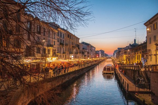 Naviglio Milano: ristoranti e locali illuminati lungo il canale al tramonto. Ristorazione milanese.