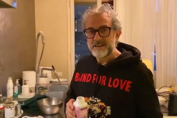 Chef Bottura in cucina durante la quarantena. Felpa nera, occhiali e lavello sullo sfondo.