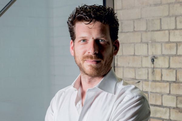 Matteo Sarzana di Deliveroo, esperto food delivery. Ritratto su sfondo di mattoni.