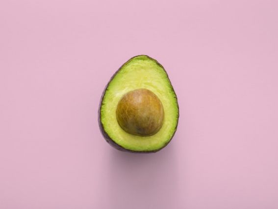 Avocado tagliato su sfondo rosa. Brand alimentare Direct-to-Consumer: accesso clienti.