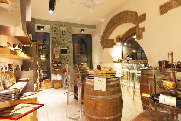 Interni enoteca INO Firenze. Tavoli barrique, vini e prodotti tipici.