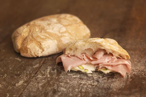 Panino artigianale con mortadella e pistacchi. Gastronomia italiana di qualità.