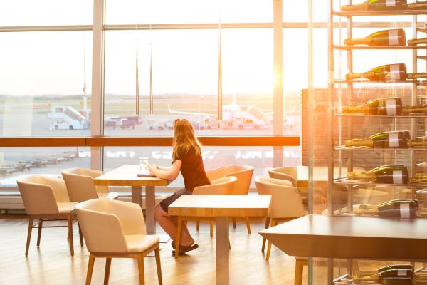 Donna in aeroporto guarda aerei. AIGRIM: azzerare canoni fissi, variabili e costi accessori.