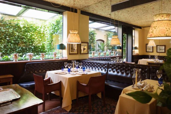 Interni eleganti del ristorante. Tavoli apparecchiati, divanetti in pelle e luci soffuse. Cucina di Max Mascia.