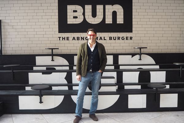 Danilo Gasparrini di Bun, catena di burger, su gradinata con logo. Delivery Bun.