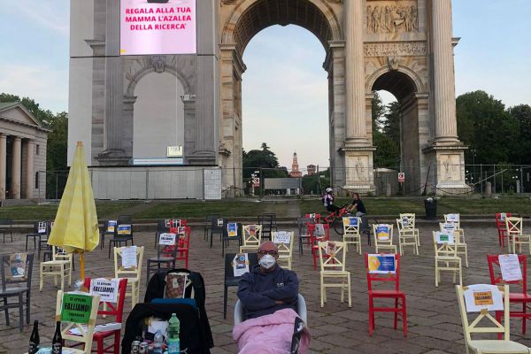 Protesta Horeca Milano: Paolo Polli seduto tra sedie vuote con cartelli Falliamo!, Arco della Pace sullo sfondo.