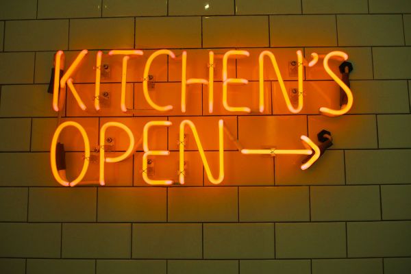 Insegna al neon Kitchen's Open su piastrelle. Fase 2 USA: cucina aperta.