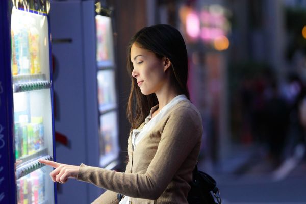 Donna al distributore automatico. Pausa sicura con vending machine. Bevande fresche e snack.