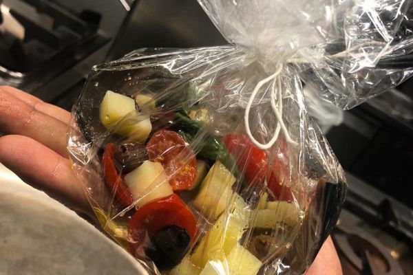 Consegna stellata: insalata gourmet in sacchetto. Ingredienti freschi, pomodorini, olive e formaggio.