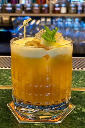 Cocktail Scilla per il World Gin Day. Drink arancione con ghiaccio, menta e decorazione.