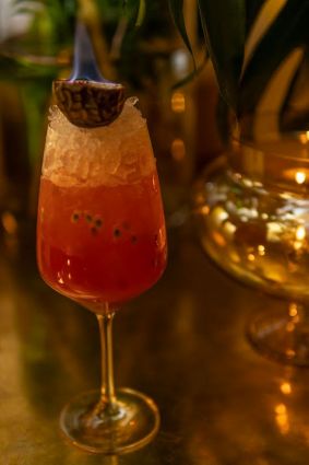 Cocktail Gin Day: drink rosso con ghiaccio e frutto della passione in fiamme.