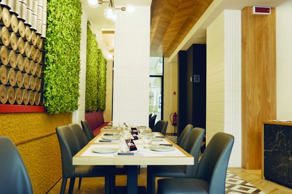 Interni del ristorante Fresco, cool della tradizione napoletana. Tavolo apparecchiato, decorazioni con verde verticale.