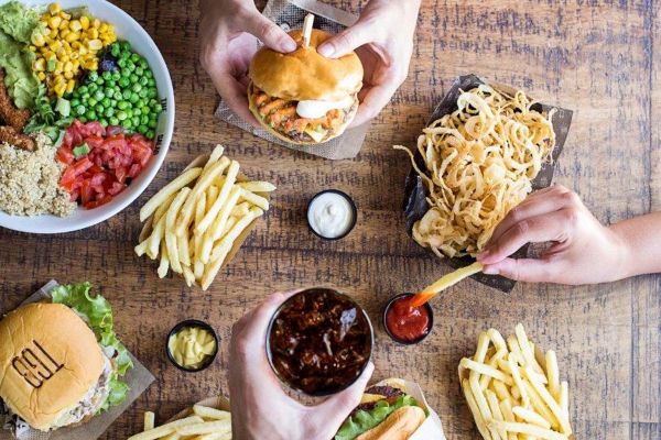 Ristorazione Restalia: tavolo con hamburger TGB, patatine fritte, anelli di cipolla e bibita.