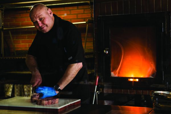 Chef taglia carne alla griglia. Cucina Acqua e Farina, Gruppo Ethos. Passione, etica e cultura del cibo.
