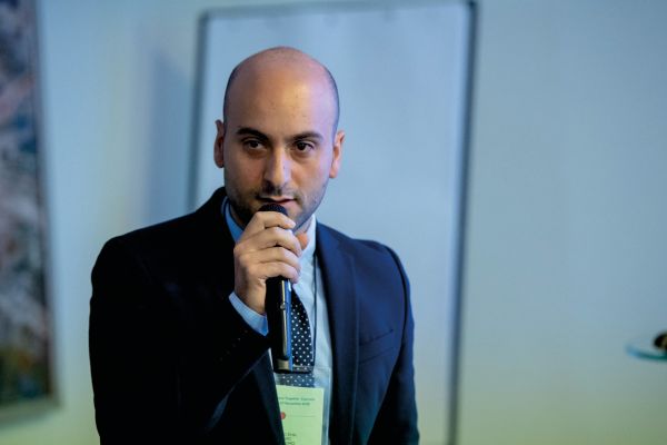 Uomo con microfono a evento grossisti bevande. Relatore parla di offerta prodotti.