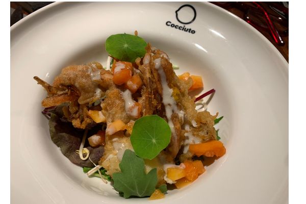 Granchio fritto di Cocciuto, un piatto internazionale. Specialità di pesce con salsa e decorazioni vegetali.