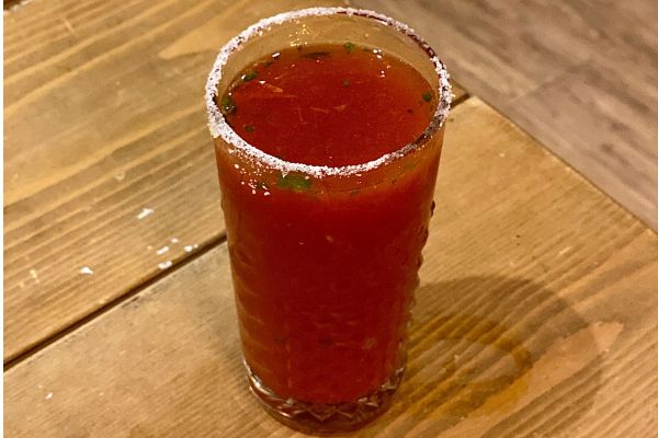 Cocktail di birra Scarnera. Bevanda rossa con bordo salato su tavolo di legno.