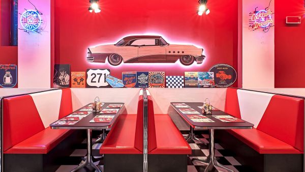 Interno di America Graffiti Fiumicino: divanetti rossi, auto vintage decorativa, atmosfera USA anni '50.