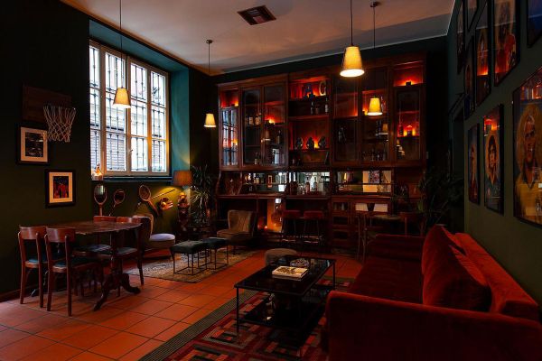 Interno accogliente del Caffè della Pusterla. Arredamento vintage, divano rosso, illuminazione calda. Flavio Angiolillo.