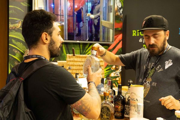 Roma Bar Show: bartender mostra bottiglia di liquore al cliente. Evento annullato, info e aggiornamenti online.