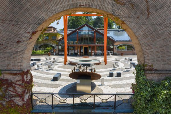 Terra Moretti: Piazza con scultura, sedute e architettura moderna. Franciacorta, Lombardia.