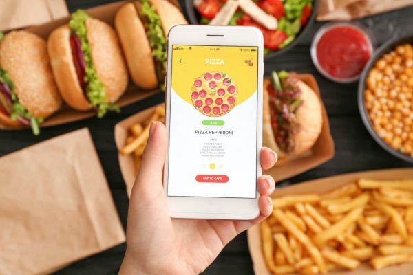 Foodservice contactless: Ordine pizza da app su smartphone. Hamburger, patatine e insalata. Customer experience digitale.