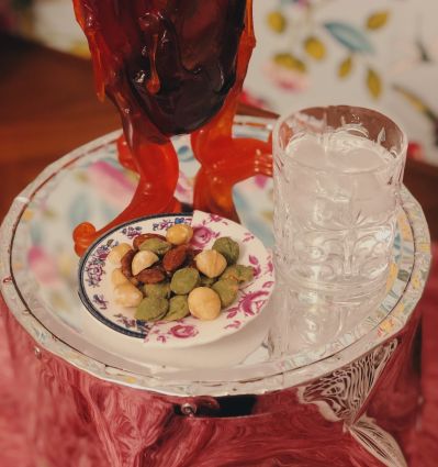 Aperitivo Food Experience: cocktail Nio, frutta secca Noberasco e acqua ghiacciata su tavolino specchiato.