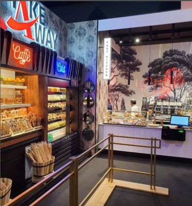 Interno locale take-away Costa Group: scaffali con cibo, insegne luminose, bancone fast kitchen. Design moderno.